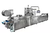 Thermoformmaschine mit integrierter Folienzuführung und Siegelstation für die Verpackung unterschiedlicher Produkte.